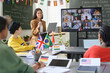 © Mediaphotos - Group of students during online conference via video chat in classroom with female teacher talking, copy space
