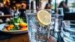 © Bebek - A glass of sparkling water with a lemon slice on a table in a restaurant.