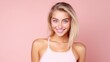 © Iona - A smiling young woman in a light pink top stands confidently against a soft pink background, radiating joy and vitality.