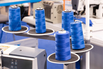 Poster - Spool of thread on an industrial sewing machine in a garment factory, industrial textile background, sewing factory, clothing manufacturing