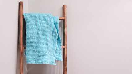 Poster - A blue and white towel is hanging on a wooden ladder. The towel is neatly folded and is positioned at the top of the ladder. cleaning concept background with space for text