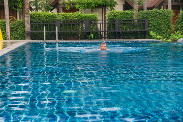 Wall Mural - Man swimming in resort pool, surrounded by tropical lush greenery, enjoying refreshing dip and relaxing in the clear blue water on Phi Phi island, Thailand. Luxury travel and tourism