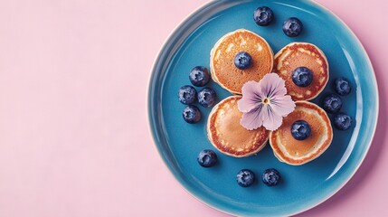 Poster -   Blue plate crowned with pancakes smothered in blueberries, then layered with blueberries on top and at the base