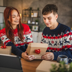 young couple wrap gift during video call, holiday spirit shines bright