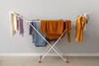 © Pixel-Shot - Clean winter clothes hanging on dryer near light wall