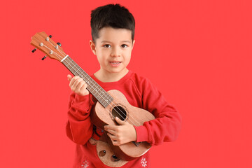 Canvas Print - Cute little Asian boy playing guitar on red background