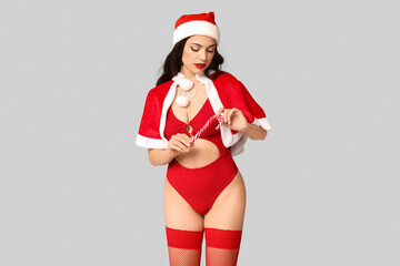 Poster - Beautiful young sexy woman in lingerie and Santa hat with candy cane on grey background