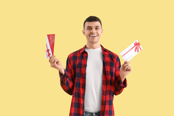 Sticker - Young man with gift vouchers on yellow background