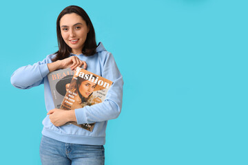 Wall Mural - Beautiful young woman with magazines on blue background