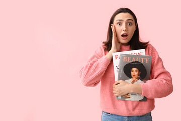 Wall Mural - Shocked young woman with magazines on pink background