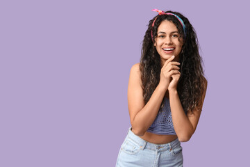 Poster - Stylish African-American woman wearing top and jeans on lilac background