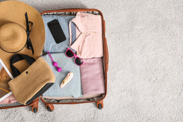 Wall Mural - Open suitcase with clothes, beach accessories, sex toys and mobile phone on light background