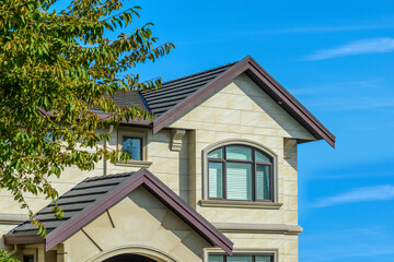 A perfect neighborhood. Houses in suburb at Fall in the north America. Top of a luxury house with nice window over blue sky.