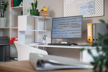 Programmer's desk with computer monitor and folders in office