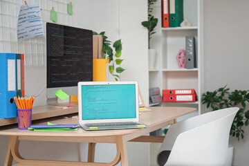 Canvas Print - Laptop with code on programmer's desk in light office, closeup