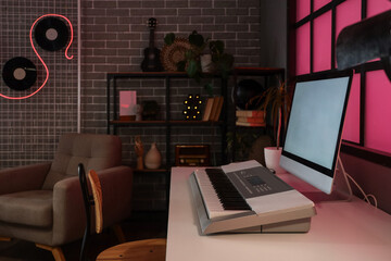 Podcaster's workplace with computer and synthesizer in dark studio