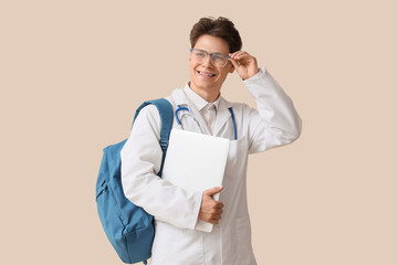 Sticker - Male medical intern with backpack and laptop on beige background