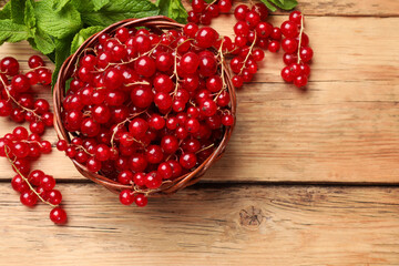 Sticker - Fresh red currants in basket and mint on wooden table, flat lay. Space for text