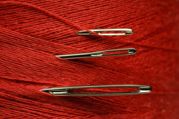 Wall Mural - Spool of red sewing thread with needles, macro view