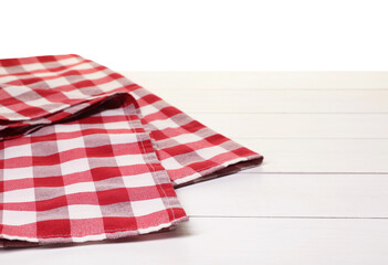 Wall Mural - Folded tablecloth with checkered pattern on wooden table against white background