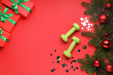 Wall Mural - Dumbbells, fir tree branches, Christmas baubles and gift boxes on red background, flat lay. Space for text