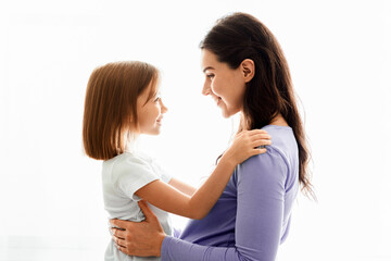 Lovely pregnant mother and little daughter cuddling over white background, family portrait