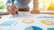 © Kunut - person analyzing business charts and graphs while taking notes, showcasing focused approach to data presentation and planning. workspace is bright and organized, enhancing productivity