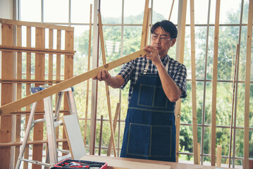 DIY craftsperson asian man working wood heap carpenter objects woodwork desk. Architect man hands use ruler measure hammer home improvement. Wooden builder carpenter repairing construction workshop