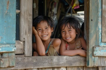 Wall Mural - Two asian children looking out of the window of a wooden house