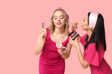 Poster - Beautiful young women applying decorative cosmetics on pink background