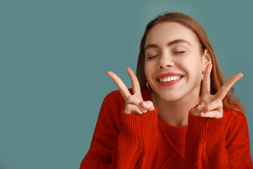 Wall Mural - Pretty young woman showing peace gestures on blue background