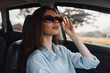 © SHOTPRIME STUDIO - Woman in sunglasses, hand on head, back seat of car, looking out window contemplatively