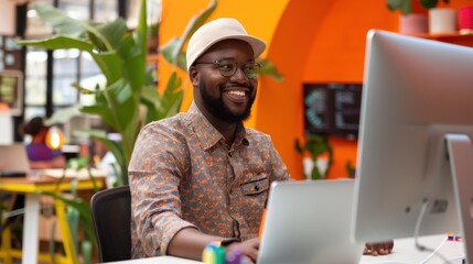 Fototapete - A man is sitting at a desk with a laptop and smiling