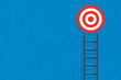 © MR.DEEN - Step ladder and target, ambition, achievement, concept of goal and success, copy space, isolated on blue paper background