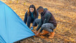 © Prostock-studio - Multiracial young couple setting tent, camping together in autumn forest