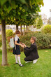 © Maria - Dad and daughter in school uniform on the lawn under a tree. education in primary school.