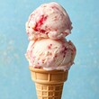 © fotofabrika - Delicious scoops of strawberry ice cream piled high on a crispy cone against a pastel blue background