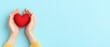 © Skip Monday - Heartfelt Gesture of Love and Care - Hands holding a red heart on light blue background with copy space. Concept of empathy and compassion.