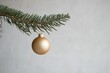 © ChaoticMind - A gold ornament gracefully suspended from a rustic pine branch set against a plain background, radiating simple elegance and festive tranquility.