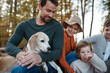 © Halfpoint - Portrait of family sitting in the middle autumn forest. Nuclear family with dog spending weekend outdoors.
