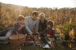 © Halfpoint - Portrait of family with two kids having picnic in autumn nature, eating fruits and cheese.