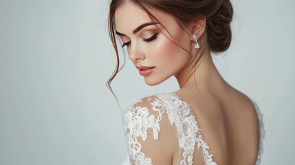 Back view of a sophisticated lady posing against a white background in an open back wedding gown. stylish outfit that shows off the shoulders. details of the wedding. A trim female model. Jewels.