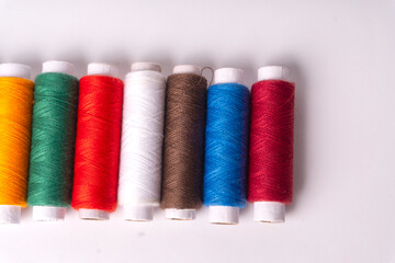 Colorful sewing thread set and needles isolated on background.