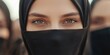 © Alena - Eyes of Muslim woman covered with headscarf, closeup. Crowd of young women in traditional black Muslim hijabs black with covered faces on city street among crowds of people.