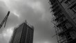 © VK Studio - Gloomy cityscape view of towering construction, reaching into a somber gray sky, framed by urban structures.
