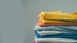 © VK Studio - A stack of colorful clothing items folded neatly, artfully arranged against a simple backdrop, showcasing tidy textiles.
