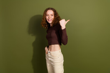 Canvas Print - Photo of shiny attractive young lady dressed brown outfit showing thumb back empty space isolated khaki color background