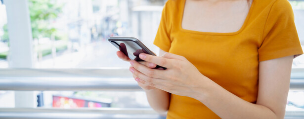 Woman holding smartphone while walking in the urban city. The concept of using the phone is essential in everyday life.