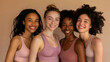 © Ayan - Smiling fit multi ethnic girls, four happy diverse young women models wearing sportswear tops bonding on beige background advertising natural beauty body care, group yoga fitness trainings. Portrait