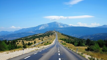 winding road leads to majestic mountain range in france. gray road contrasts with rich plants of tre